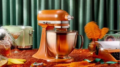 KitchenAid&reg; Tangerine Twinkle Stand Mixer, surrounded by glamorous pearls, feathers, and disco balls