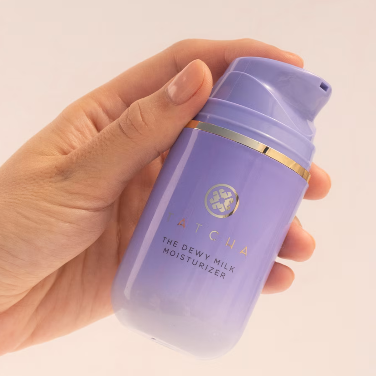 Hand holding up Tatcha The Dewy Milk Moisturizer 