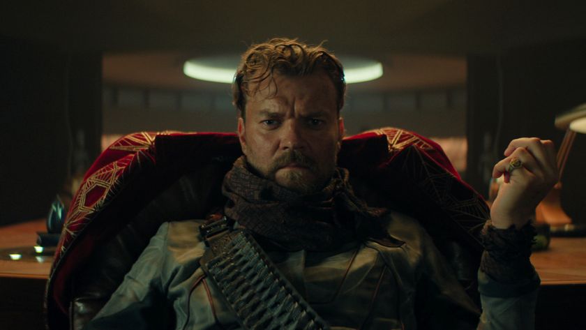 a brooding man sits in a high-backed chair thinking