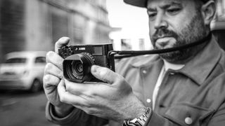 Street photographer shooting with a Fujifilm X100V in an urban environment