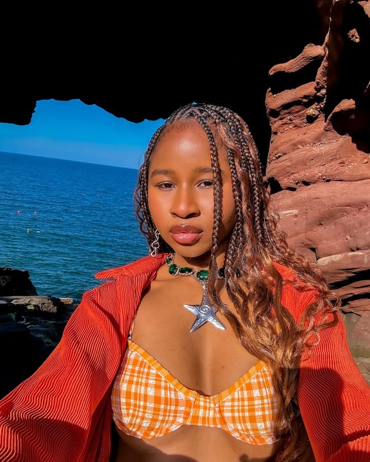 A woman wearing goddess braids in a swimsuit on the beach.