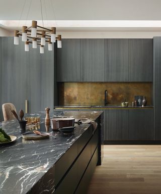 Dark grey woodgrain kitchen with black marble look worktops
