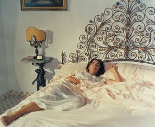 Marie Laforêt laying in bed wearing a white silk slip nightgown in Plein Soleil (Purple Noon).