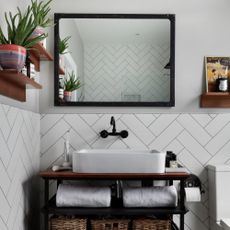 A basin unit in a bathroom with tiled walls, a square basin and mirror