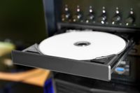 Desktop PC with open disc tray. White printable DVD disc inside.