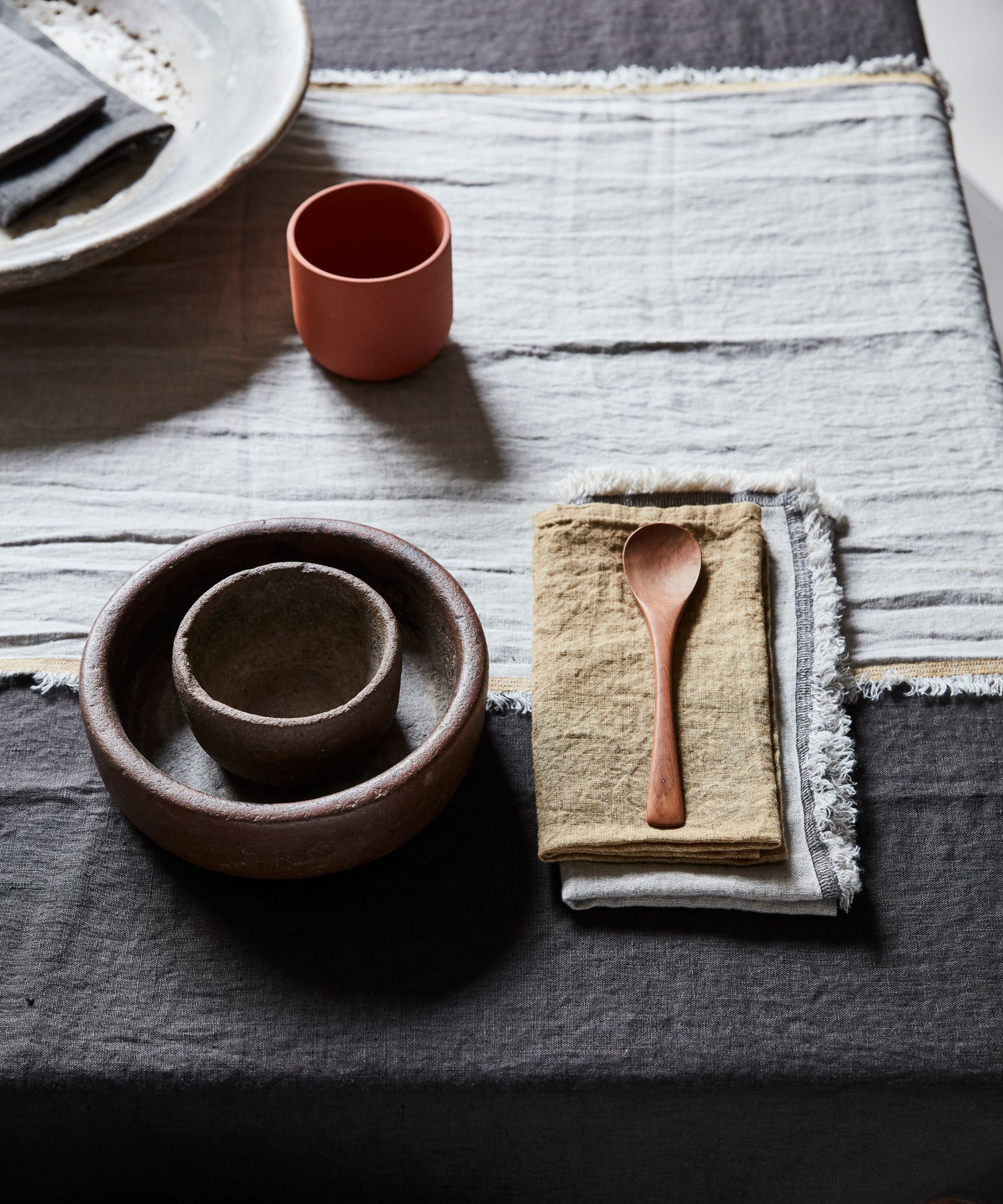 minimalist table setting with ceramics, linens and wooden spoon