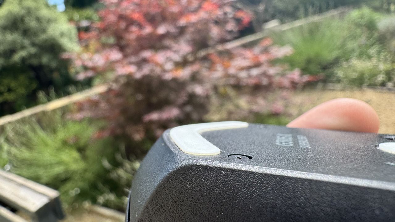 Logitech G305 X Superlight gaming mouse, held in a hand outside