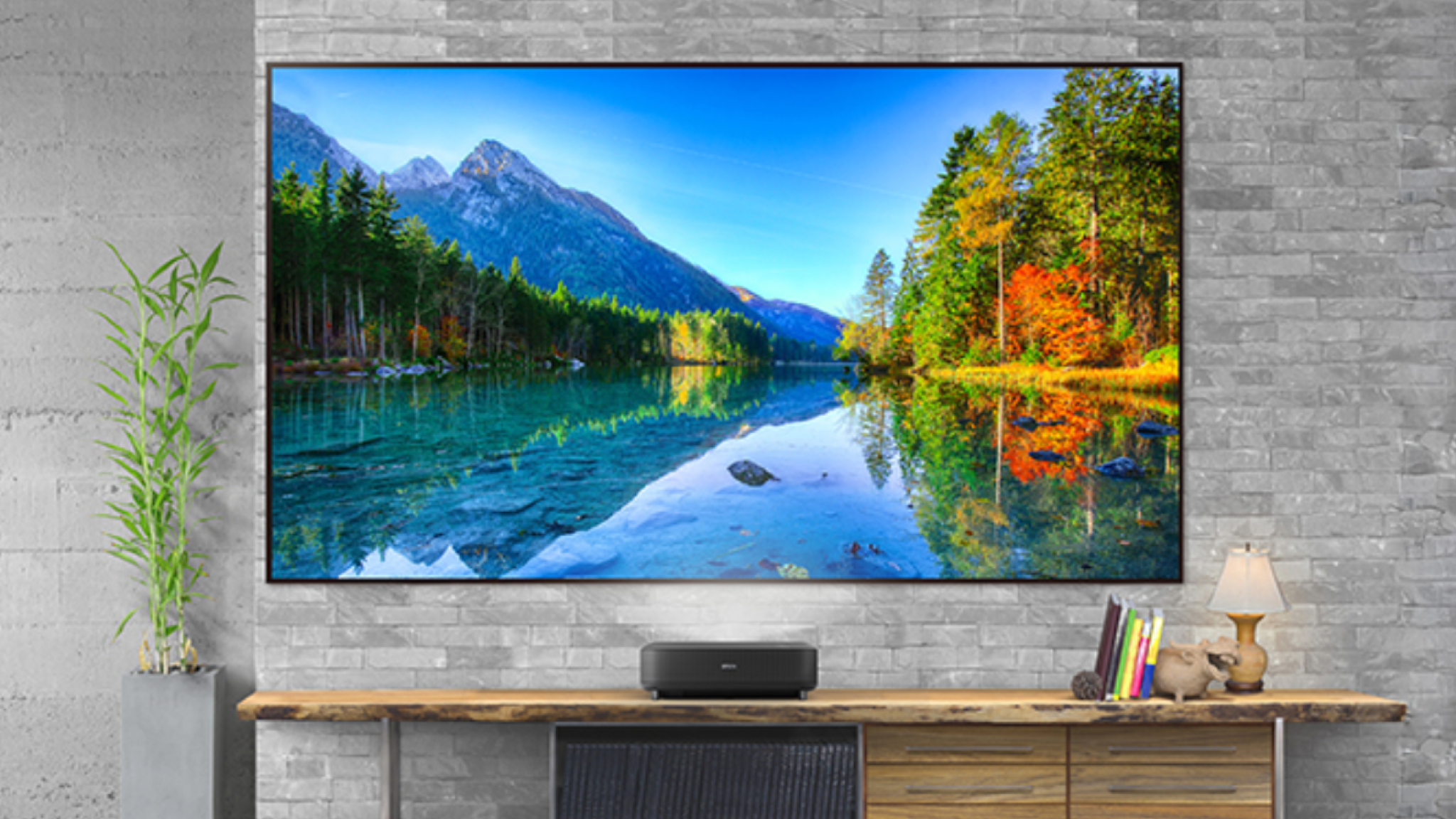 Epson Lifestudio Grand projecting a large scenic image on a screen in front of a grey brick wall