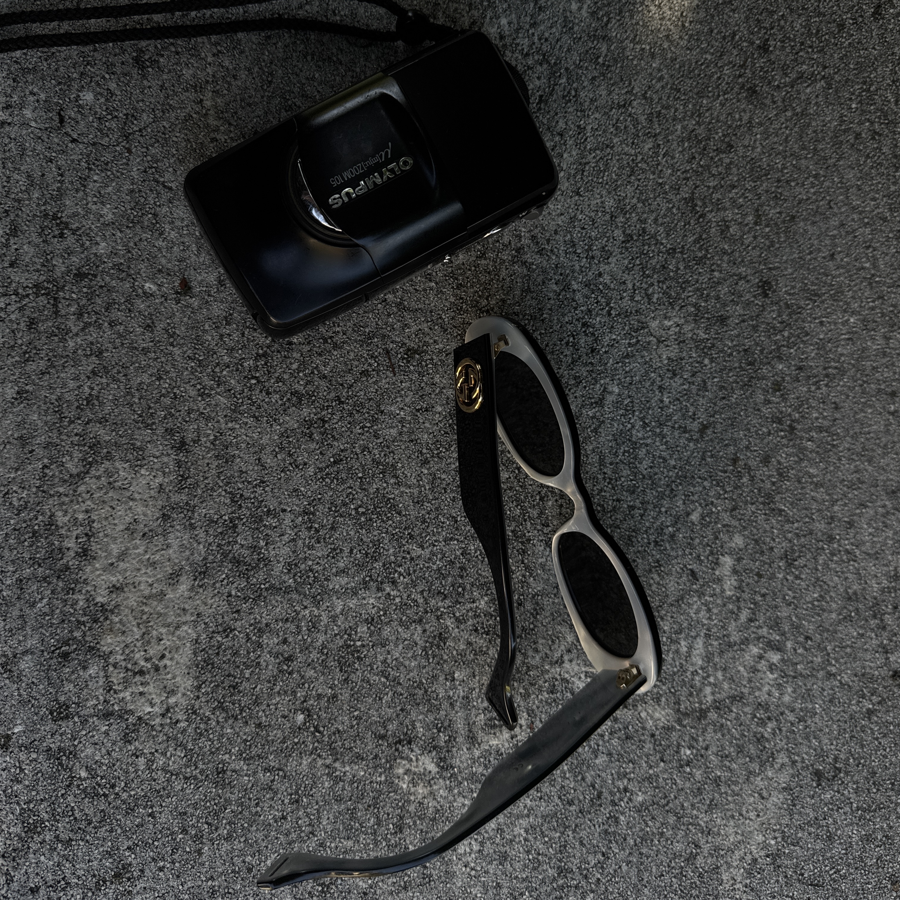 Gucci sunglasses and camera on concrete