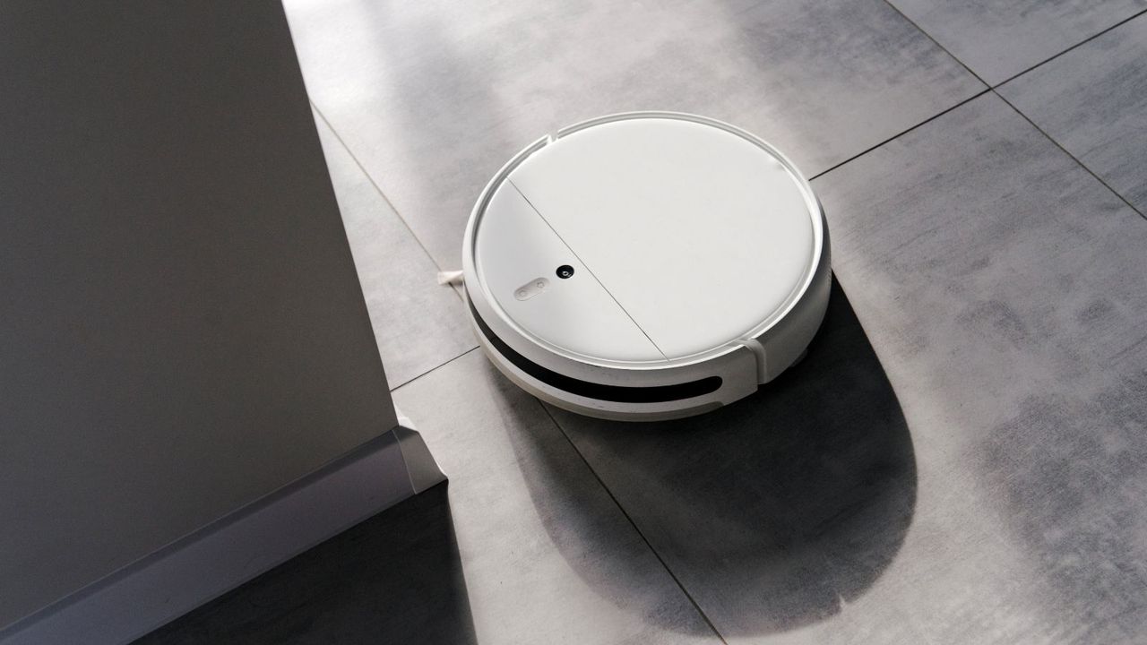 A white robot vacuum on a grey tiled floor