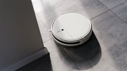 A white robot vacuum on a grey tiled floor