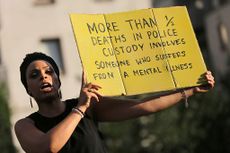 A Black Lives Matter protester in London holds a sign about the correlation of mental illness and police shootings