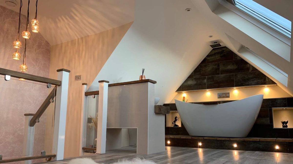 A bedroom with freestanding bath under sloping eaves in a loft converted using Telebeam