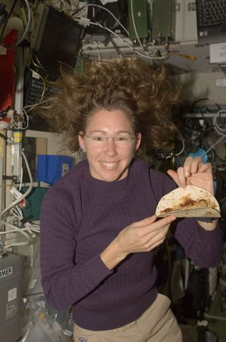 Astronaut Sandra Magnus, Expedition 18 flight engineer, poses with food made with a tortilla wrap on the International Space Station in 2008.