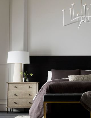 White bedroom with black headboard and wooden chest of drawers by Arteriors