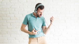 Man wearing headphones playing air guitar