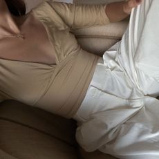 Creator @deborabrosa wearing white trousers with a beige long-sleeve top