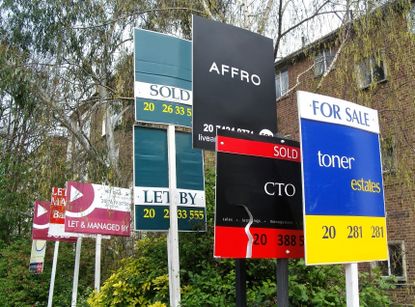 Property signs outside a block of flats advertising homes for sale, let or sold