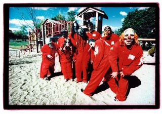 Slipknot wearing red overalls in a sandy playground