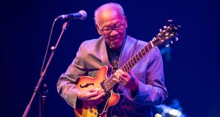 Ska and reggae pioneer Ernest Ranglin plays his Gibson semi-hollow onstage in 2016.
