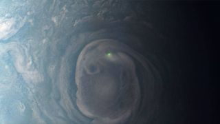 a green dot of lightning flashes in the swirling clouds of jupiter's thick atmosphere