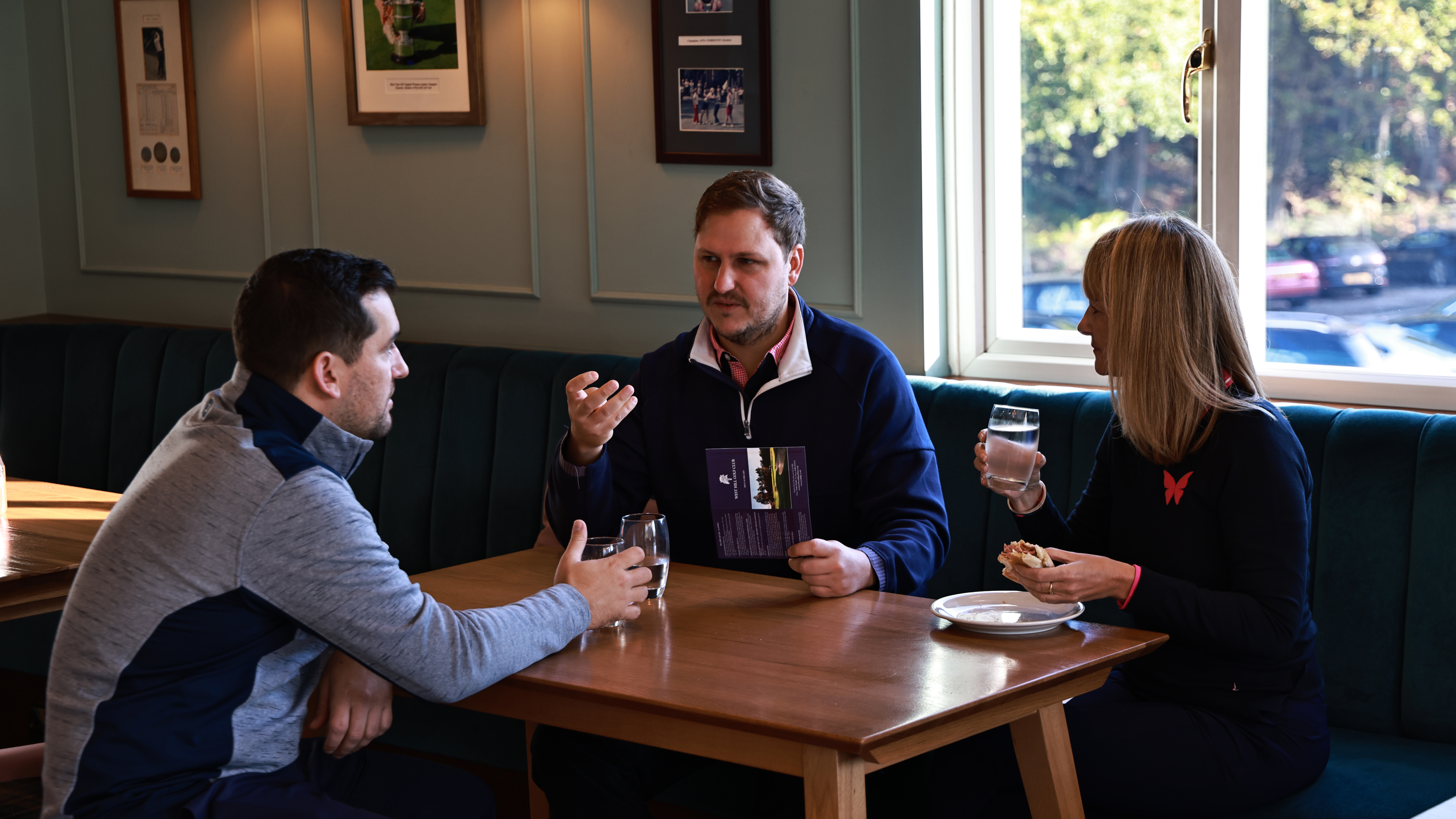 Nick Bonfield, Alison Root and Sam De'Ath having a drink in the clubhouse after their round and discussing their scores