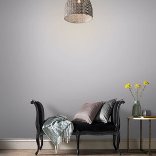 room with grey wall and black sofa with cushions andd side table