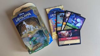 A Lorcana starter deck next to an unopened pack and some cards on a table