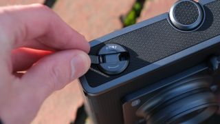 A hand turning the wind lever on a Fujifilm Instax Wide Evo camera