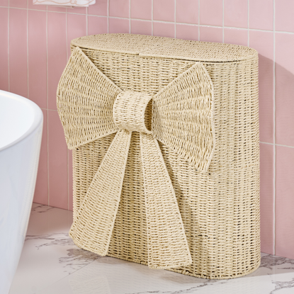 Next natural woven bow laundry sorter in pink tiled bathroom.