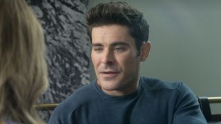 Zac Efron with a blue long sleeve shirt sitting in his starring role opposite Nicole Kidman in Netflix's A Family Affair (2024).
