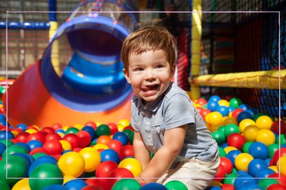Little boy having fun at indoors playground, playing with multi colored balls - stock photo