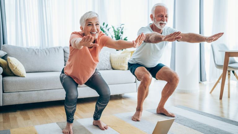 Older couple perform a HIIT style workout at home together
