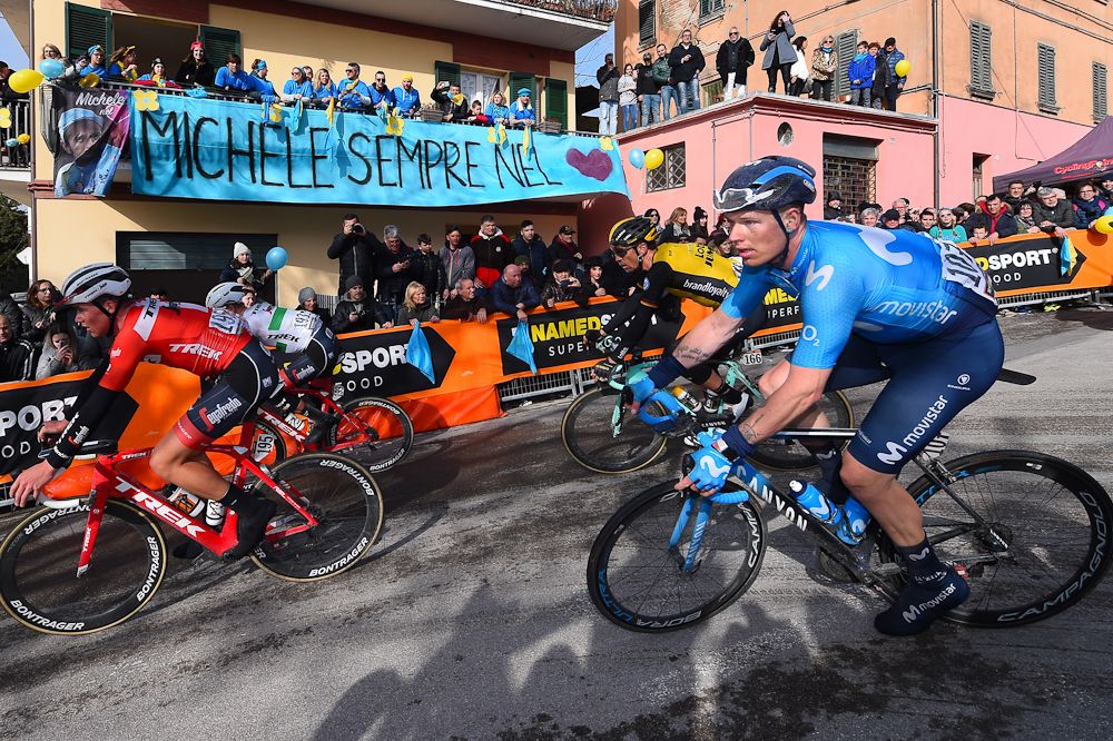 The Tirreno-Adriatico peloton passes a banner honouring Michele Scarponi in Filottrano
