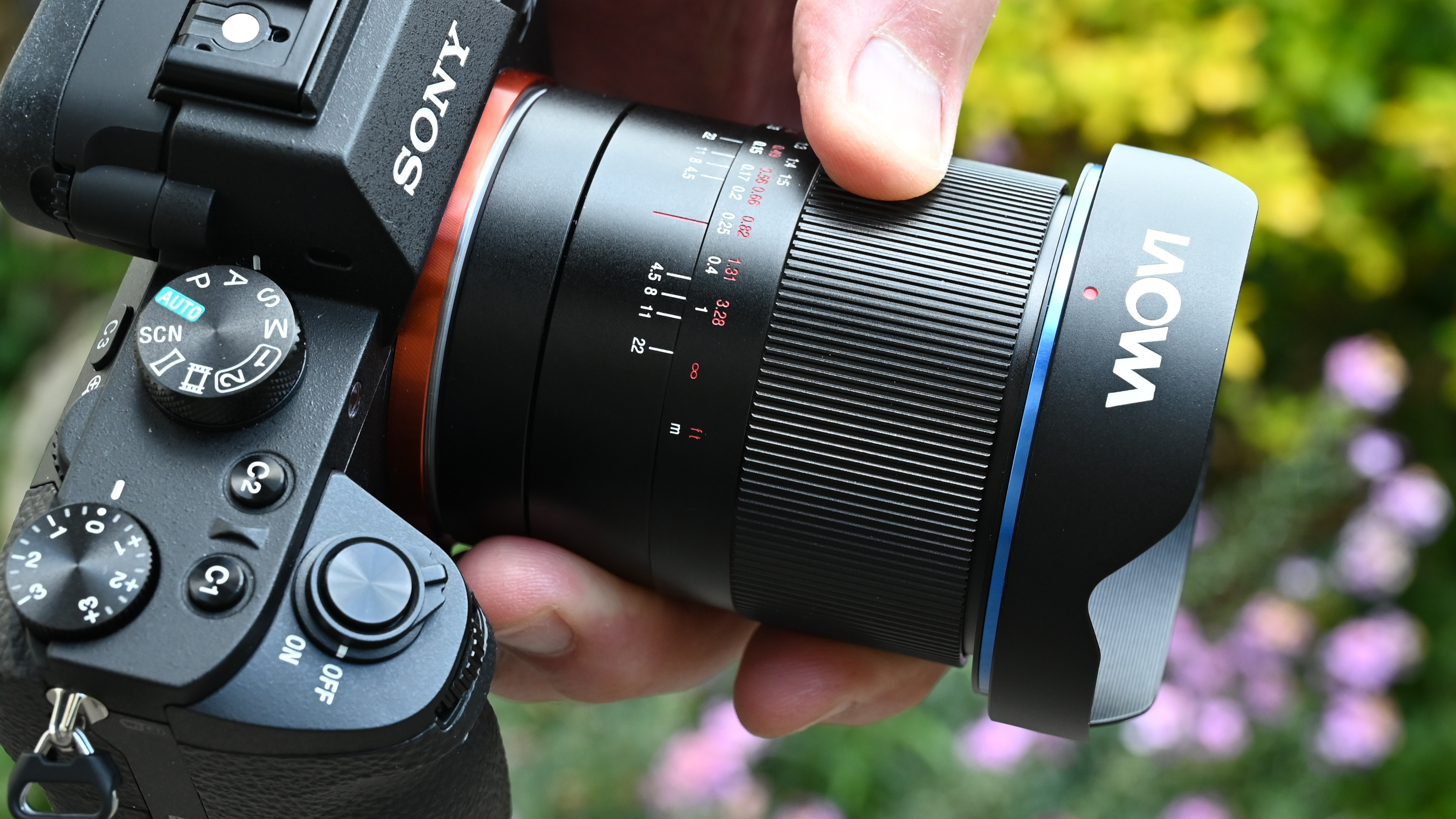 Laowa 15mm f/4.5 0.5x Macro product shot with lens held in hand