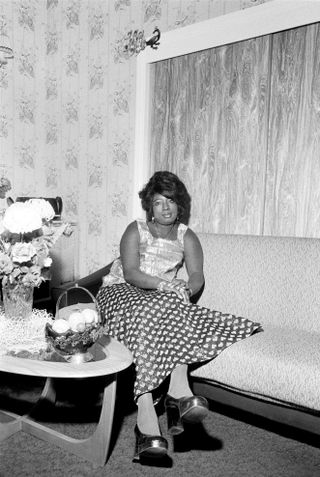 a portrait of an individual sat on a couch next to a coffee table