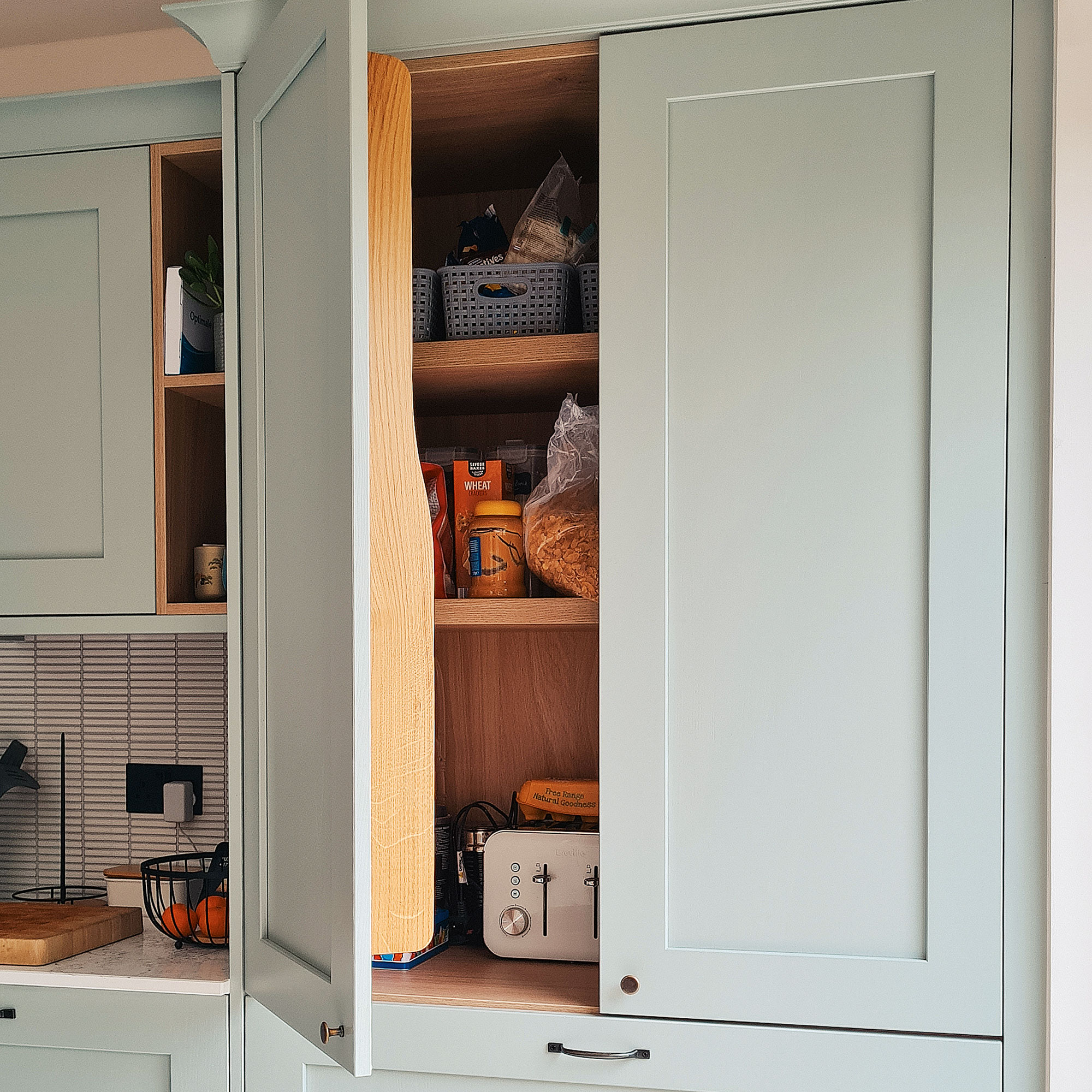 Green kitchen cabinets with black bar stools around kitchen island