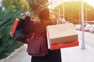 A woman holding an array of black, red, and white shopping bags.