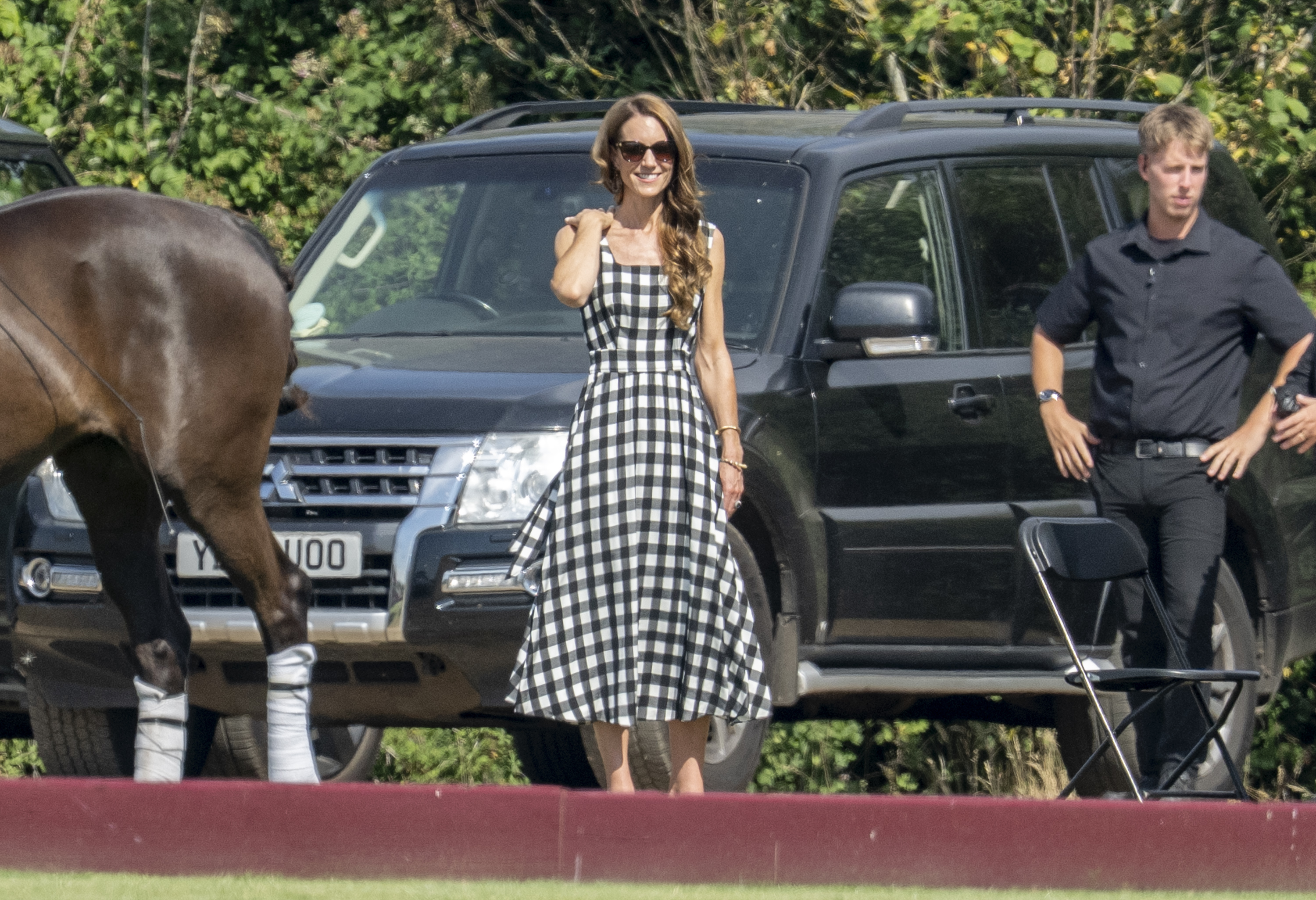 Princess Kate wearing a gingham dress standing next to a horse
