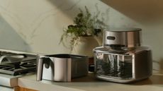 Stainless steel Cosori air fryer and its air fryer drawer sitting on a kitchen counter