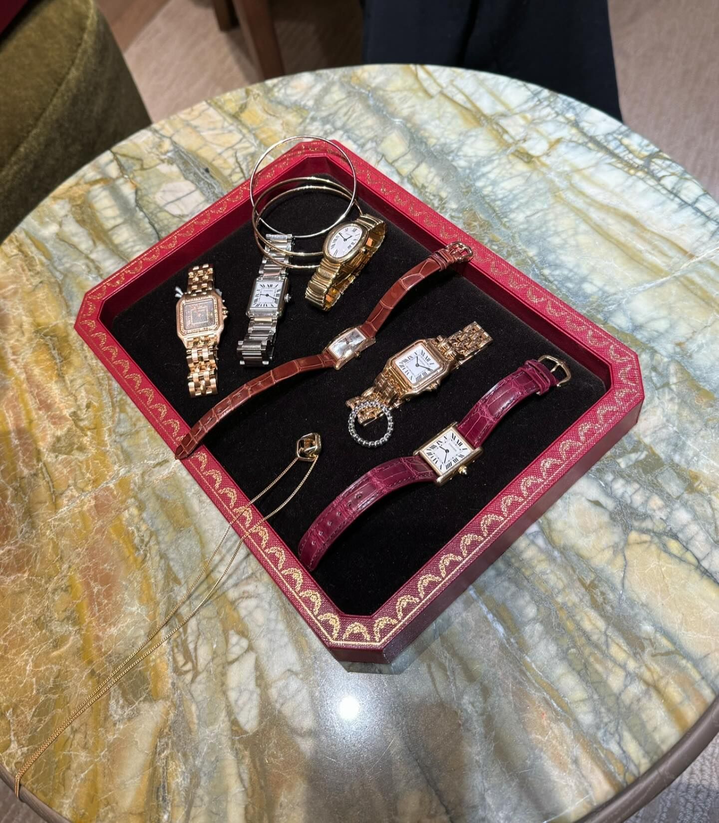 An image of the Cartier Baignoire, Cartier Tank and Cartier Panthère lying flat on a red box as captured inside the brand's boutique.
