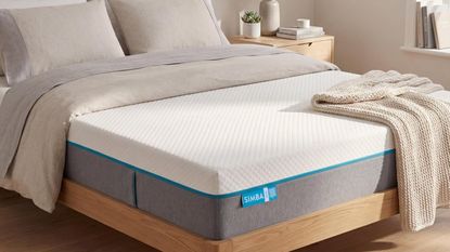 Simba mattress on wooden bed frame with neutral bedding and wooden bedside tables