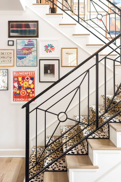 white hallway and staircase with leopard print runner, metal handrail, gallery wall