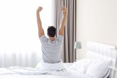A man stretches when he wakes up in the morning.