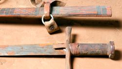 A close of up a rusty sword with a brown hilt and its brown, leather scabbard.