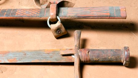 A close of up a rusty sword with a brown hilt and its brown, leather scabbard.
