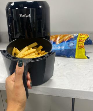 Cooking fries in air fryer with packaging in background