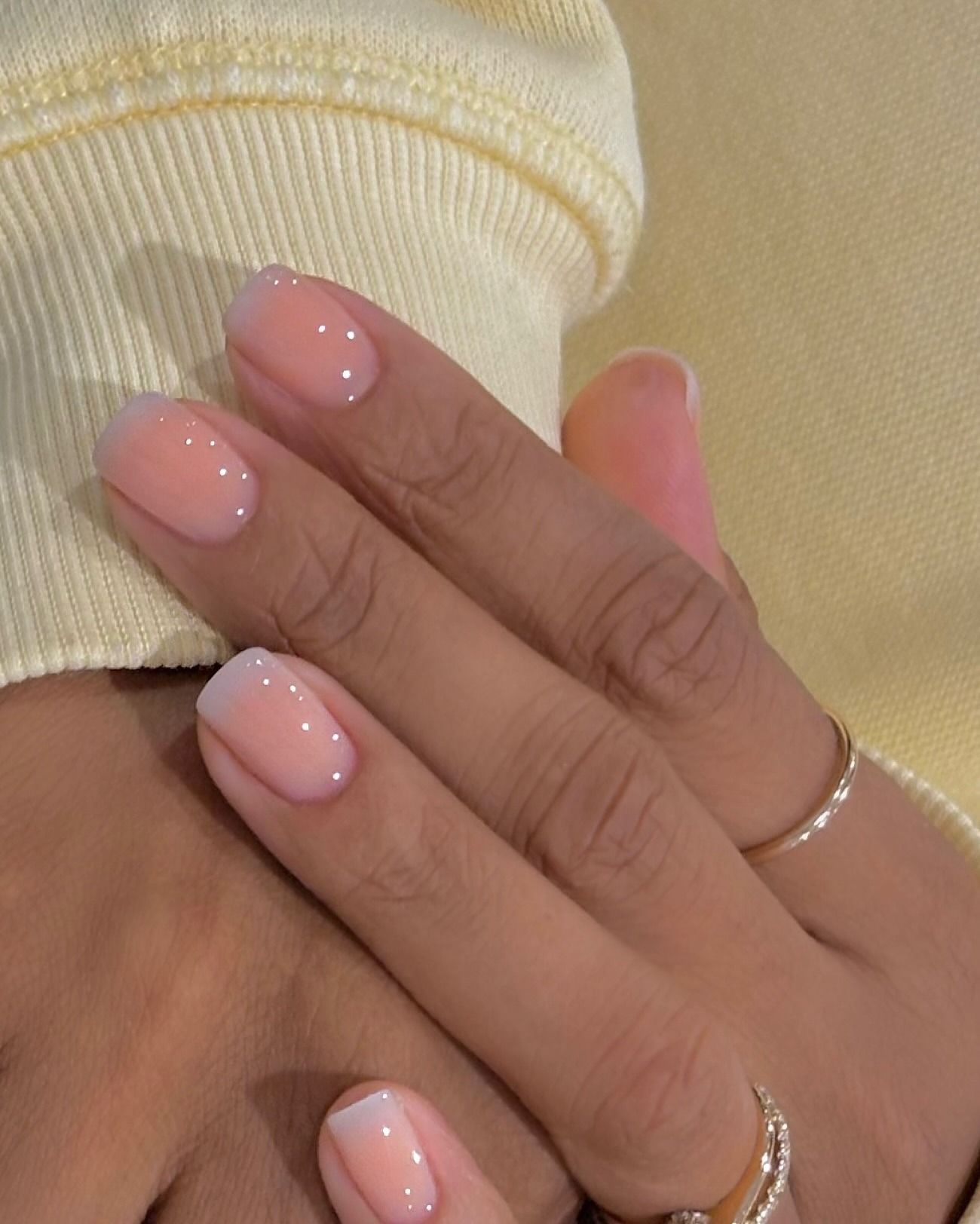 A photo of sheer peach nails with a cream ombre French tip