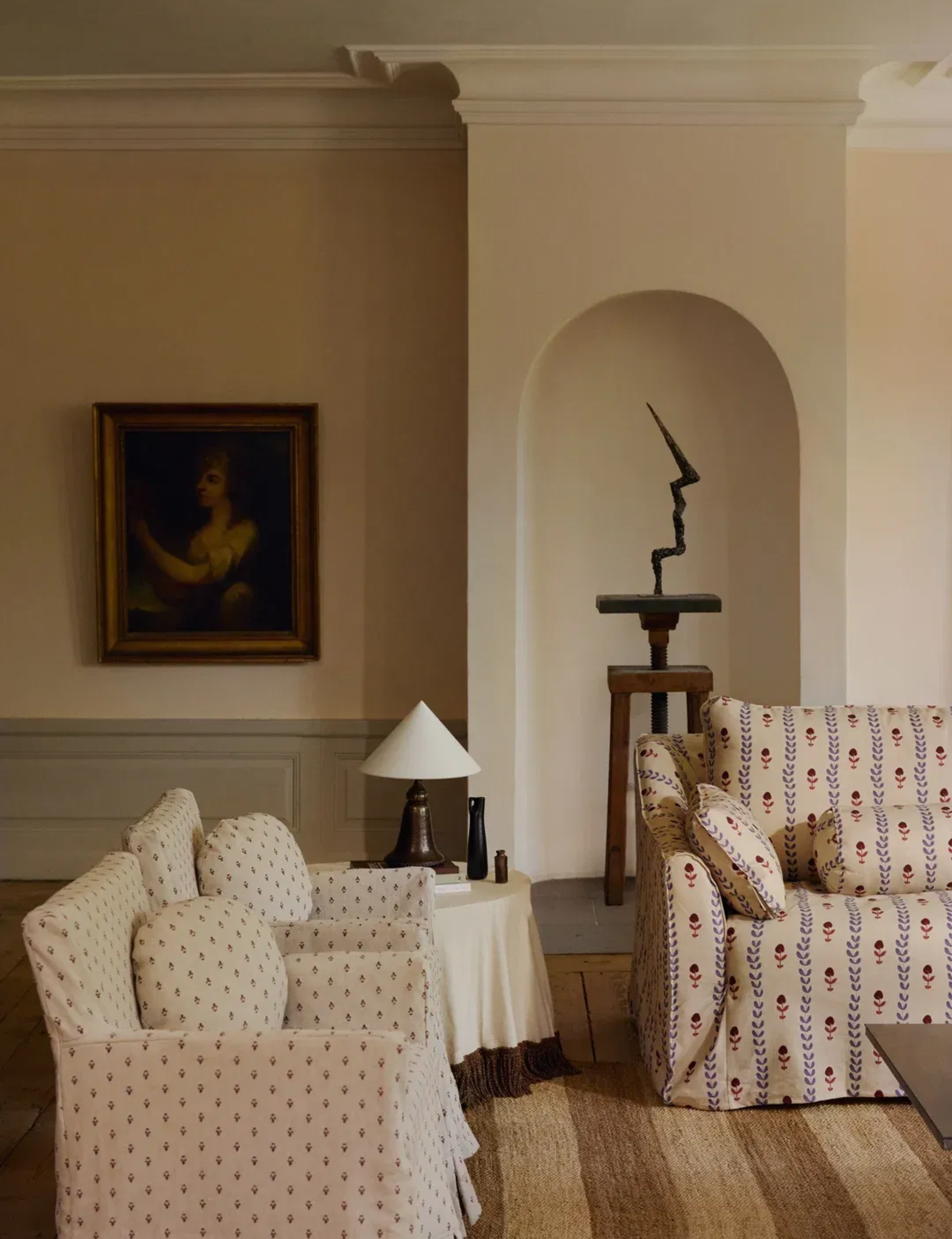 Sophisticated living room featuring patterned slipcovered furniture, an antique oil painting, and a modern sculpture