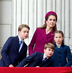Prince George, Princess charlotte, Prince Louis, Kate Middleton and Prince William leaning to the right looking at planes from the palace balcony